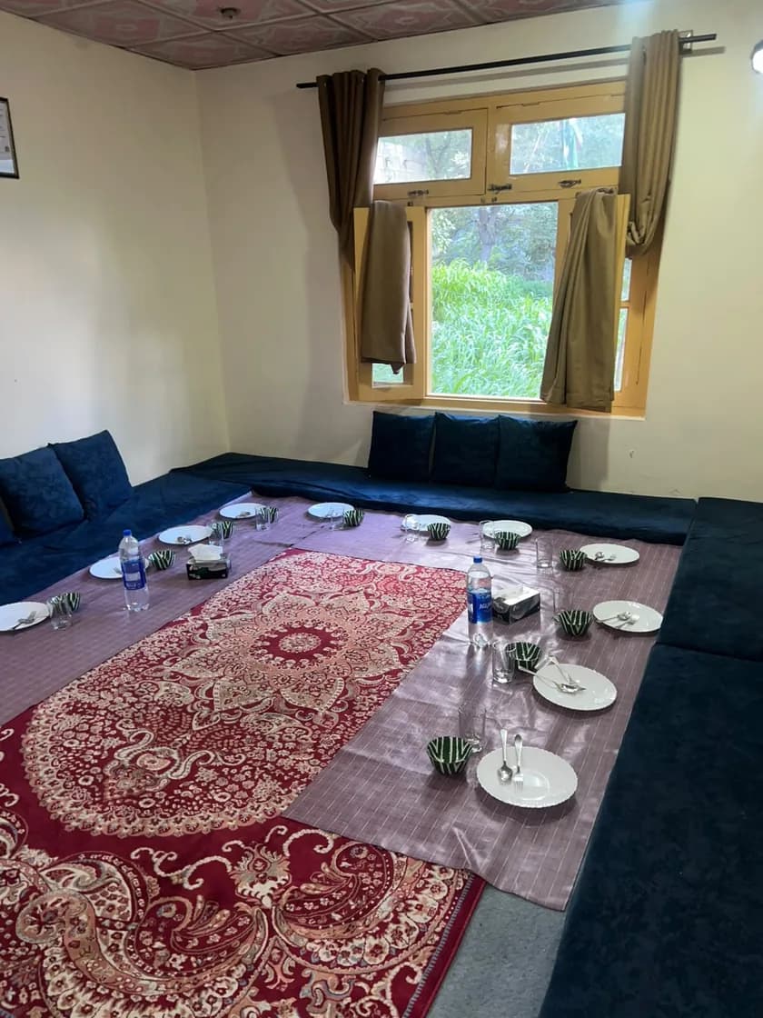 The dining room at Balti Cuisine: floor seating, a red carpet and a long cloth laid with plates